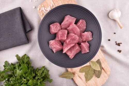 Surowe mięso gulaszowe z szynki EKO 500g w misce z przyprawami i pietruszką